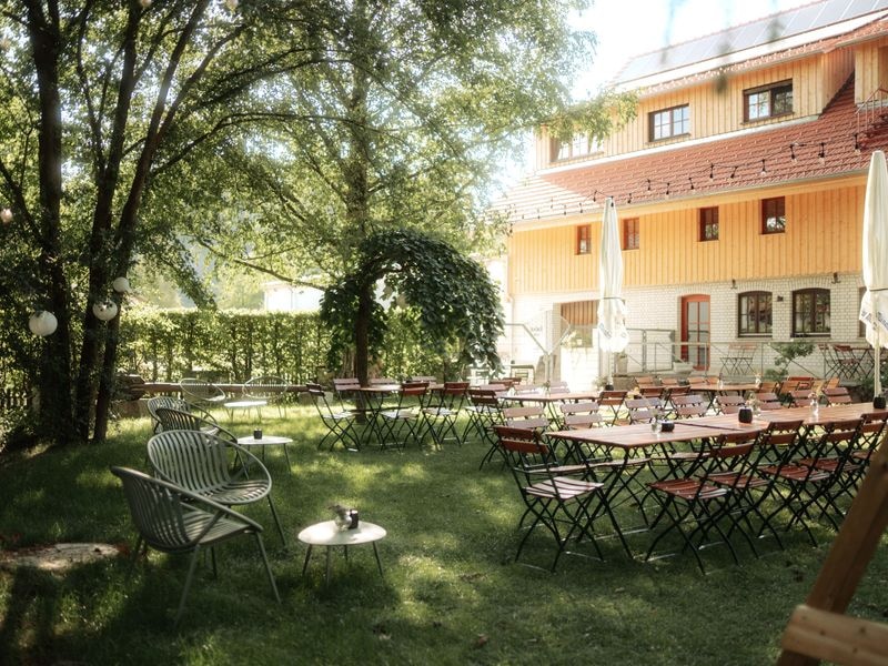 Biergarten unter alten Bäumen mit Blick auf den Hof